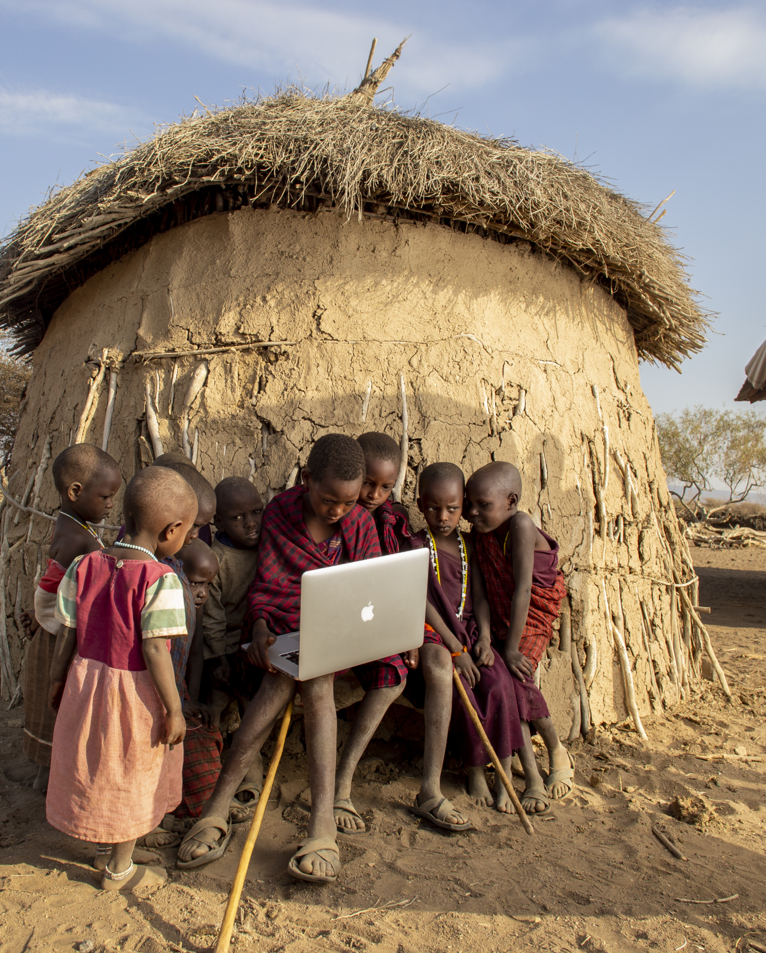 African kids outside hut with laptop